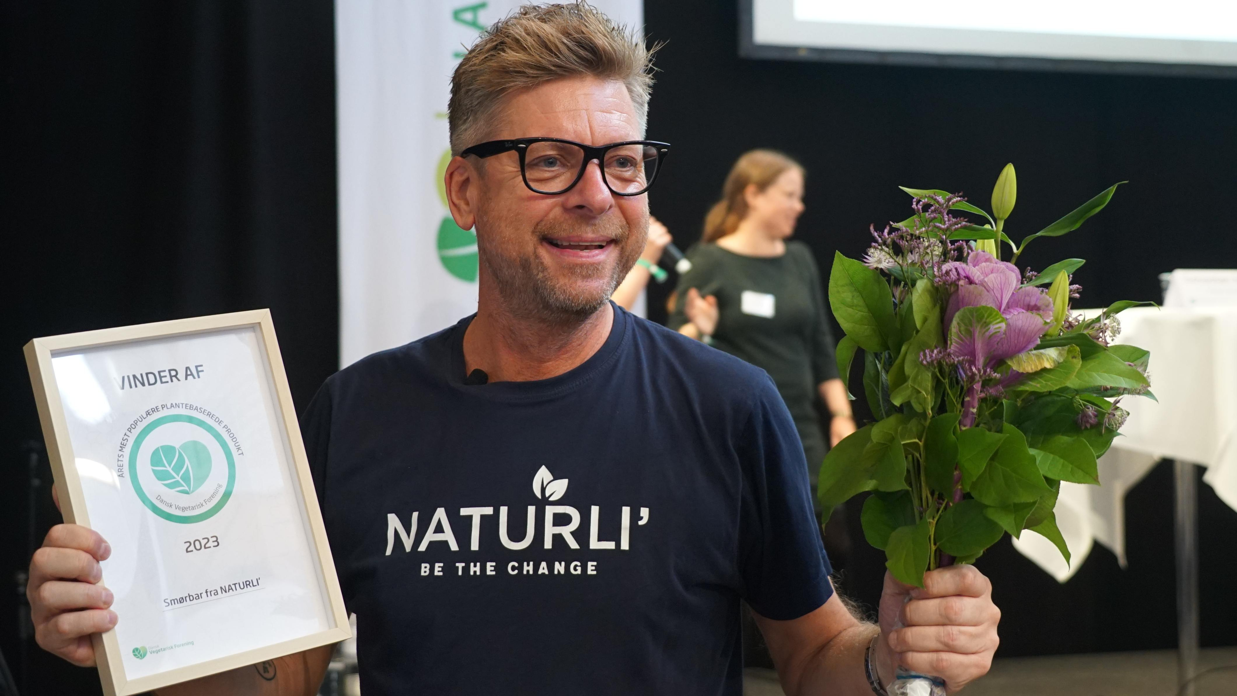 Henrik Lund står med diplom og en buket blomster
